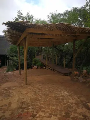 a wooden pergola with a bridge in the background at Kruger River Villas- Treetop Loft in Marloth Park