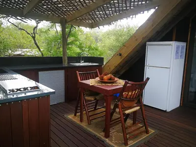 a kitchen with a table and chairs on a deck at Kruger River Villas- Treetop Loft in Marloth Park