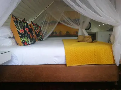 a bed with white sheets and a yellow blanket at Kruger River Villas- Treetop Loft in Marloth Park