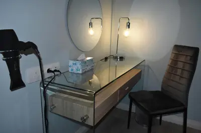 a glass desk with a chair and a mirror at Mosswood Bed & Breakfast in Graskop