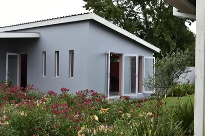 a white house with windows in a garden at Mosswood Bed & Breakfast in Graskop