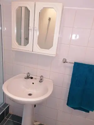 a bathroom with a white sink and a blue towel at Rural feeling Self Catering Next door to Sandton in Midrand