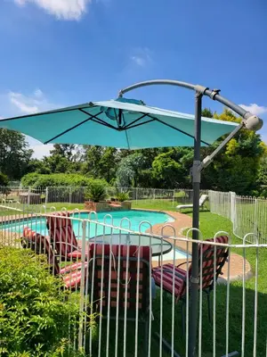a table and chairs under an umbrella next to a pool at Rural feeling Self Catering Next door to Sandton in Midrand
