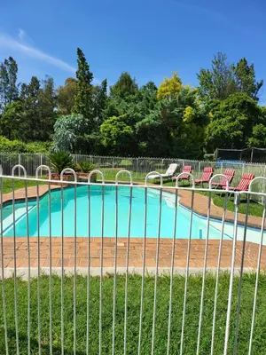 a fence with chairs and a swimming pool at Rural feeling Self Catering Next door to Sandton in Midrand
