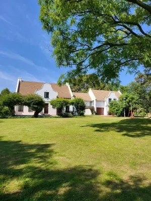 a large white house with a large yard with a tree at Rural feeling Self Catering Next door to Sandton in Midrand
