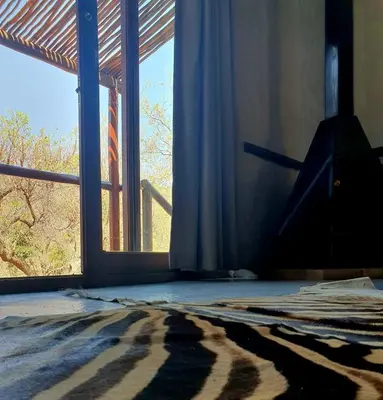 a room with a window and a bed with a rug at Rock Cottage, Bela-Bela in Bela-Bela