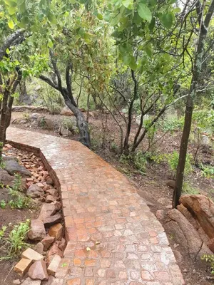 a brick path in the middle of a forest at Rock Cottage, Bela-Bela in Bela-Bela