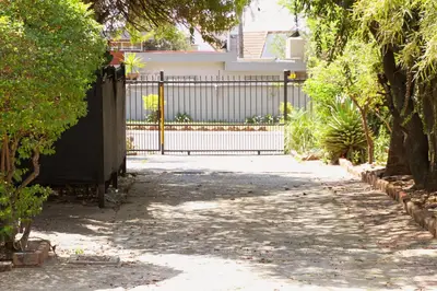 a driveway with a gate in front of a house at Beautiful Studio Cottage at Menlyn Maine in Pretoria