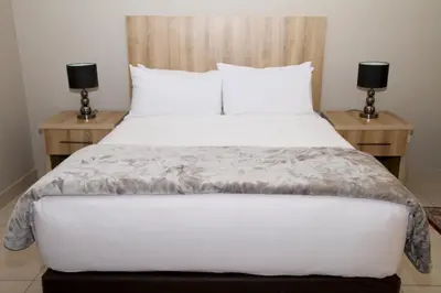 a bedroom with a large white bed with two night stands at Beautiful Studio Cottage at Menlyn Maine in Pretoria