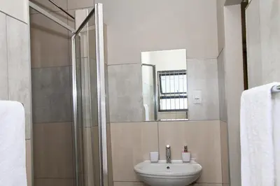 a bathroom with a sink and a mirror at Beautiful Studio Cottage at Menlyn Maine in Pretoria
