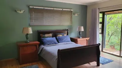 a bedroom with a bed with blue pillows and a window at Zwartkloof View, Bela Bela in Bela-Bela