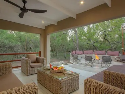 a screened in porch with a couch and a fireplace at The Den at Kruger 3479 in Marloth Park