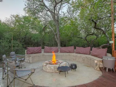 a patio with a fire pit with a couch and chairs at The Den at Kruger 3479 in Marloth Park