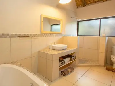 a bathroom with a sink and a tub and a toilet at The Den at Kruger 3479 in Marloth Park