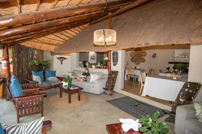 a woman sitting on a couch in a living room at Thornhill Safari Lodge in Hoedspruit