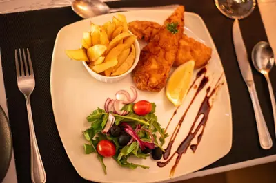 a plate of food with fish and chips and vegetables at Thornhill Safari Lodge in Hoedspruit
