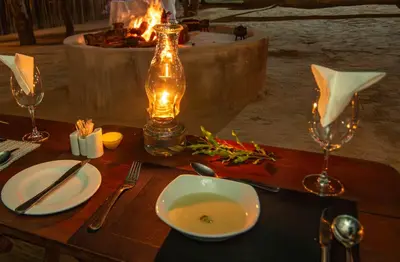 a table with a bowl of soup and a bottle of wine at Thornhill Safari Lodge in Hoedspruit