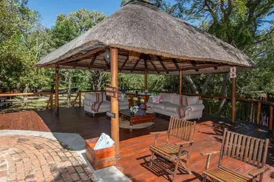a large wooden deck with chairs and a thatch roof at Thornhill Safari Lodge in Hoedspruit