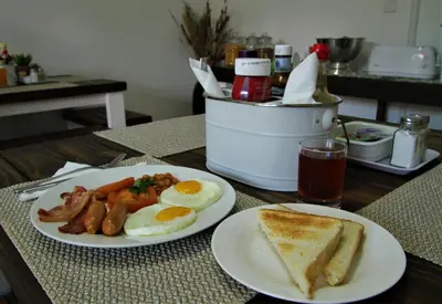 a table with two plates of breakfast food and a drink at Mahem Manor Guesthouse in Brits