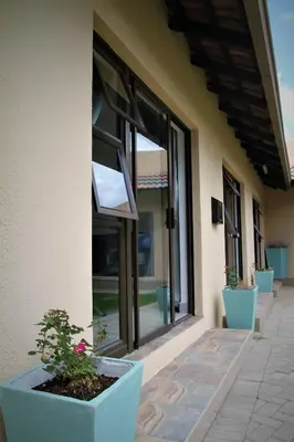 a building with large windows and potted plants on a porch at Mahem Manor Guesthouse in Brits