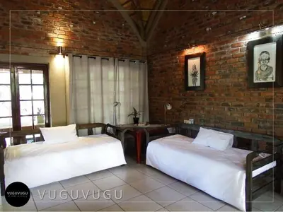 a bedroom with two beds and a brick wall at VuguVugu - At home in Africa in Marloth Park