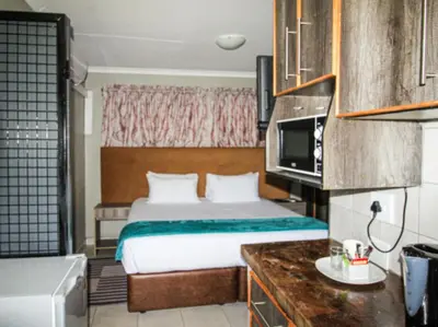 a hotel room with a bed and a microwave at PW Heights Private Guest House in Thohoyandou