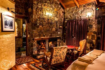 a stone room with a bed and a fireplace at Heysbrook Estate - Luxurious lodges in a private valley in Waterval-Onder