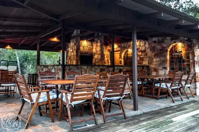 a wooden table and chairs on a patio at Heysbrook Estate - Luxurious lodges in a private valley in Waterval-Onder