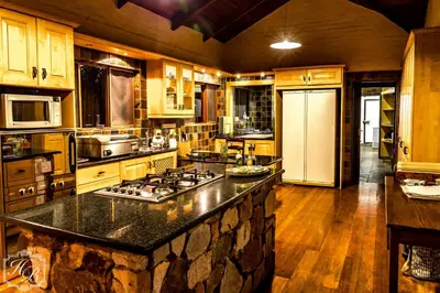 a large kitchen with wooden cabinets and a granite counter top at Heysbrook Estate - Luxurious lodges in a private valley in Waterval-Onder