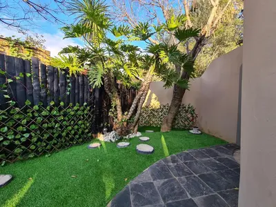 a garden with palm trees and a fence at Cozy Cabin in Midrand