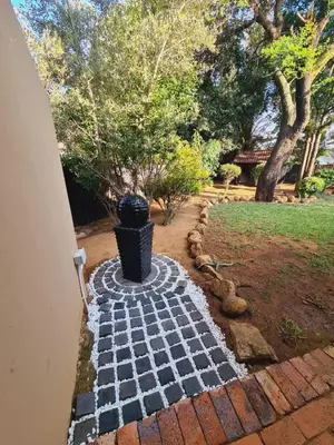 a brick walkway with a garbage can in a yard at Cozy Cabin in Midrand