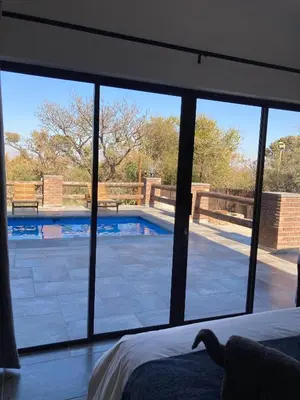 a bedroom with a view of a swimming pool through a window at 636 Itaga Safari Lodge, Mabalingwe Nature Reserve in Mabula