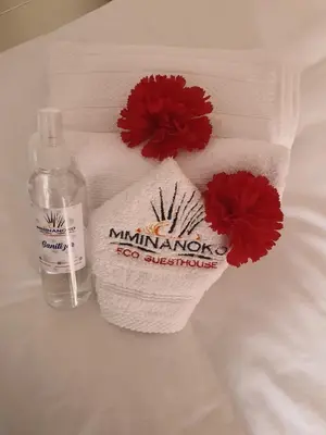 a towel with two red flowers and a bottle ofphrine at Mminanoko Eco Guesthouse in Mamphokgo