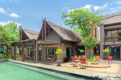 a house with a swimming pool and red chairs at Zebula Boutique Hotel in Mabula