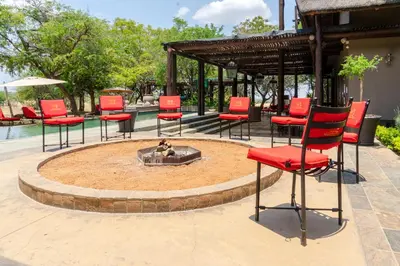 a group of red chairs sitting around a fire pit at Zebula Boutique Hotel in Mabula