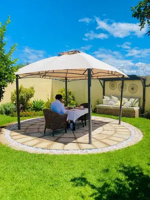 a man sitting at a table under an umbrella at Mrhali Boutique Guest House in Kwamhlanga