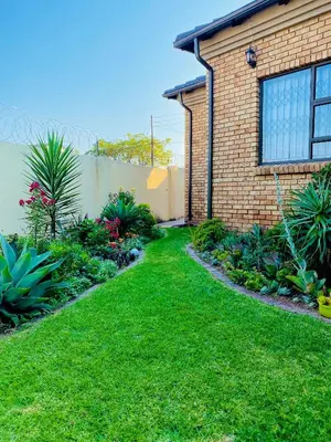 a yard with a brick house and some plants at Mrhali Boutique Guest House in Kwamhlanga