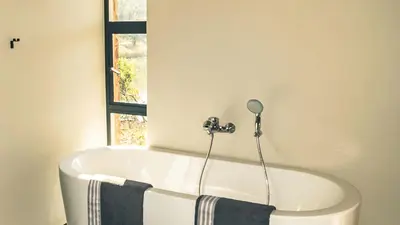 a white bath tub in a bathroom with a window at Lodge @ Bankenkloof Private Game Reserve in Tierpoort