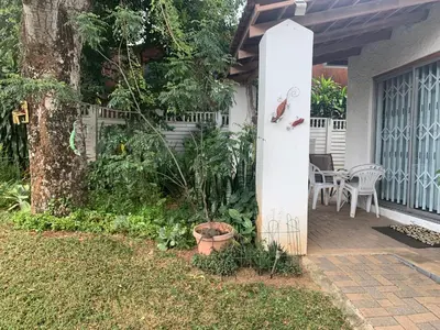 a patio with a tree and a table and chairs at Plum Cottage in Nelspruit