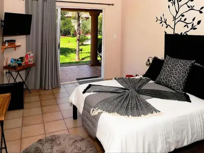 a bedroom with a bed and a door to a yard at Tamarisk Guest Lodge in Benoni