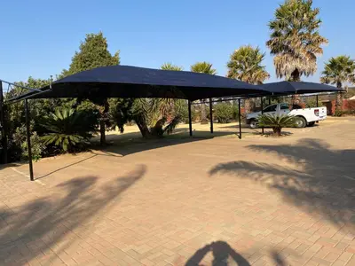 two black umbrellas in a parking lot with a truck at Tamarisk Guest Lodge in Benoni