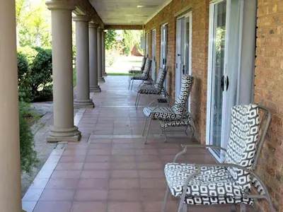 a row of chairs on a porch with columns at Tamarisk Guest Lodge in Benoni