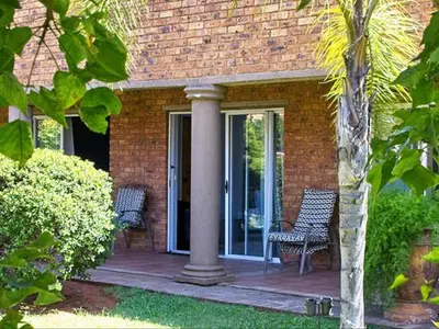 a brick house with two chairs on a porch at Tamarisk Guest Lodge in Benoni