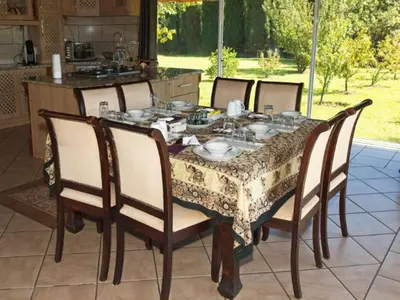 a dining room table and chairs with a table and a kitchen at Tamarisk Guest Lodge in Benoni