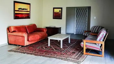 a living room with a red couch and a table at Buffalo House @Bankenkloof Private Game Reserve in Tierpoort