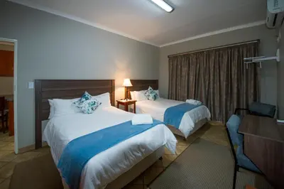 a hotel room with two beds and a desk at @ Marula in Mokopane