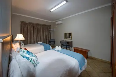 a hotel room with two beds and a desk at @ Marula in Mokopane