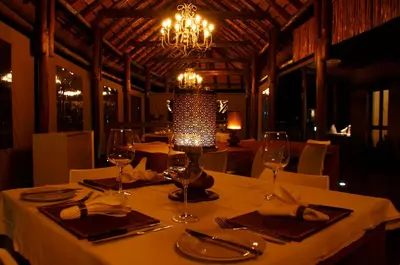 a table with wine glasses and a lamp on it at Moditlo River Lodge in Hoedspruit