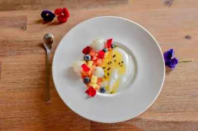 a white plate with fruit salad on a table at Moditlo River Lodge in Hoedspruit