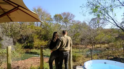 a man and a woman standing next to a hot tub at Mologa River Lodge in Rust de Winter